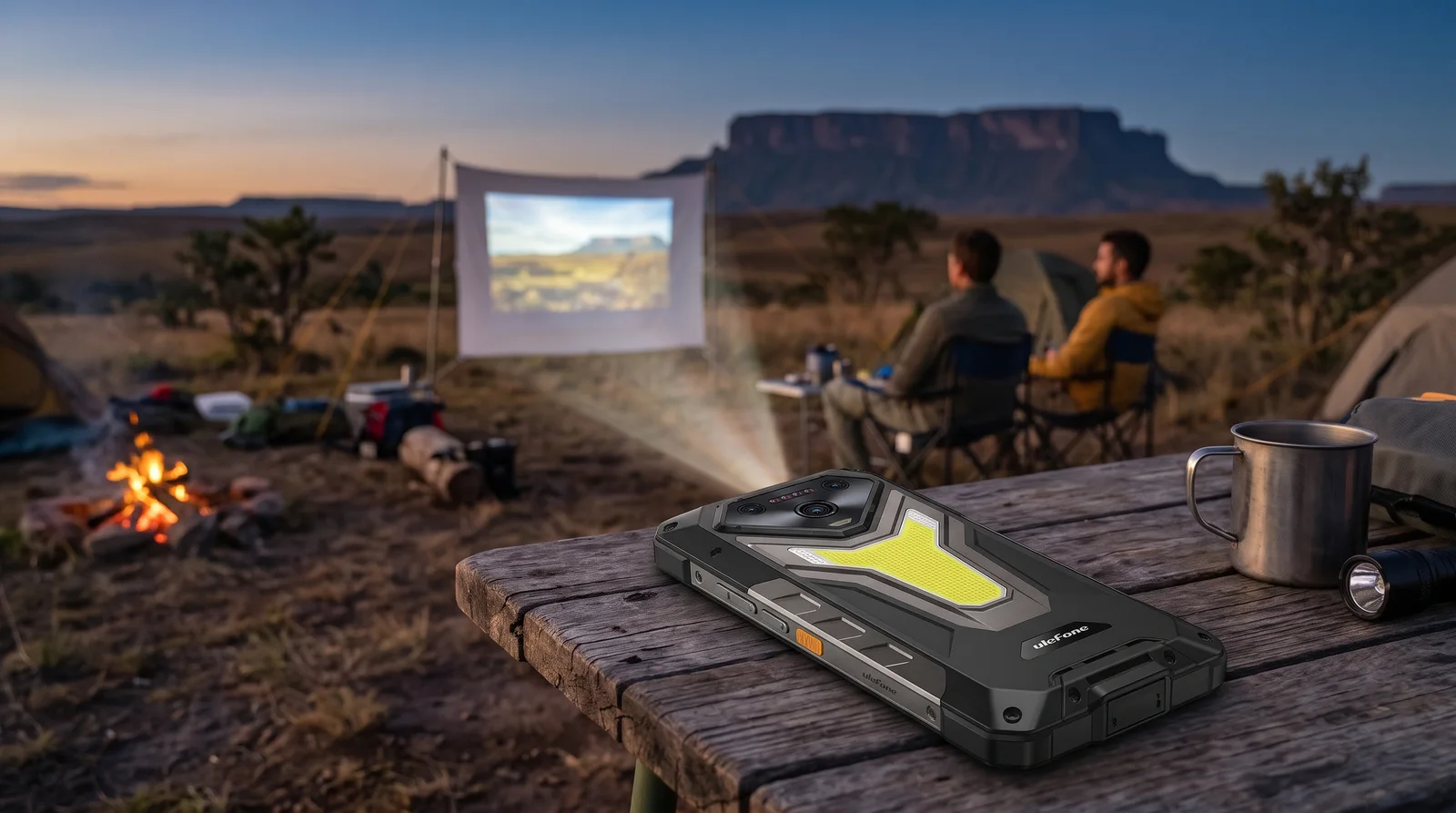 Ulefone Armor 34 Pro sobre una mesa de campamento proyectando una película desde su borde superior en la Gran Sabana al atardecer